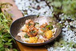 Fresh fried eggs with shrimps covered by herbs in pan table in garden