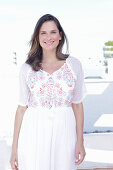 Langhaarige Frau in weißem Sommerkleid mit bunter Stickerei