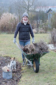 Woman with wheelbarrow full of garden waste, dog Zula