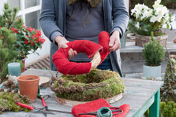 Homemade moss wreath cake with candle: woman wraps straw baked in red felt