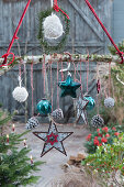 Weihnachts-Mobile als hängende Deko mit Sternen, Zapfen, Kugeln und Woll-Bommeln an Birkenast
