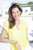 A young woman wearing a yellow sleeveless top