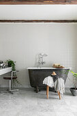 Kleine freistehende Badewanne im schlichten Bad in Grau und Weiß