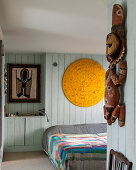 Ethnic sculpture in bedroom with pale blue wood panelling