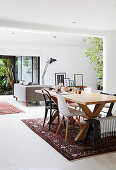 Wooden table with various chairs; couch next to terrace doors in background