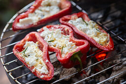 Grilled red pointed peppers filled with feta cheese and rosemary on a barbecue