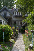 Paved path leading through summery garden to Art Nouveau house