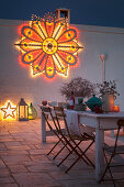 White, shabby-chic wooden table on festively decorated terrace at twilight