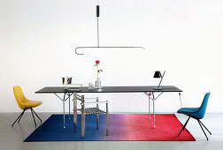 Black metal table and various designer chairs on ombré rug
