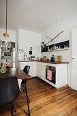 Black and white kitchen-dining room with dark wooden floor
