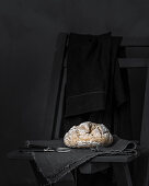 Ein hausgemachtes Brot auf Leinentuch vor schwarzem Hintergrund