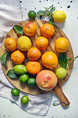 Various citrus fruits on a round wooden cutting board