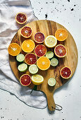 Various halved citrus fruits on a round wooden cutting board