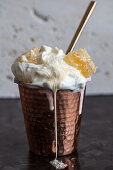 A copper cup filled with vanilla ice cream, topped with honey comb and drizzled with honey