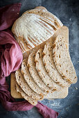 A loaf of sourdough bread slices of bread on a wooden board