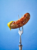 A sausage dipped in mustard on a fork