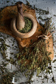 Dried mint in an olive wood mortar on a wooden board on newspaper