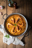 Paella with roasted shrimps on rustic table