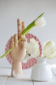 White tulip held in wooden hand
