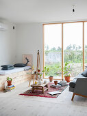 Fitted bench made from pale wood, coffee table and couch next to floor-to-ceiling window