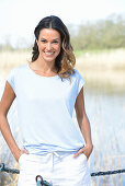 A young woman wearing a light-blue T-shirt and white shorts near river