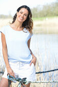 A young woman wearing a light-blue T-shirt and white shorts near river