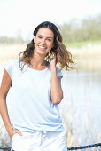 A young woman wearing a light-blue T-shirt and white shorts near river