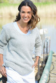 Junge Frau in grauem Pullover und weißen Shorts am Fluss