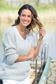 A young woman wearing a grey jumper near river