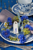 A small wreath of cornflowers, lady's mantle, and chamomile as a plate decoration