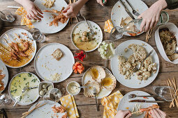 Grillfest mit Meeresfrüchten und Gemüse, teilweise schon leer gegessene Teller