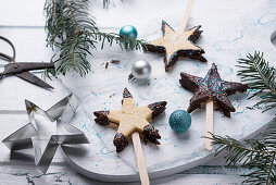 Shortbread stars on sticks filled with jam and decorated with chocolate glaze