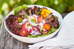 A summer salad with nectarines, feta cheese and edible flowers