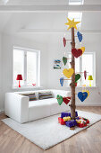 Alternative Christmas tree made from tree trunk decorated with multicoloured love-hearts