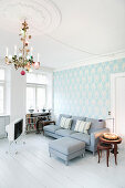 Kronleuchter im Wohnzimmer mit hellblauer Tapete und weißem Boden