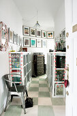 Display cabinets and gallery of pictures in hallway with chequered floor