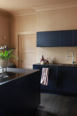 Dark blue, modern kitchen with dark floor and beige walls