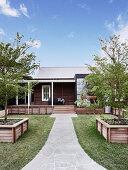 Path with flagstones through the garden to the wooden house under a blue sky