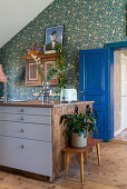 Houseplant on bench next to island counter in front of wall with floral wallpaper