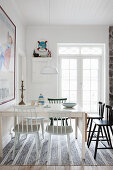Various spoke-back chairs around table in white dining room