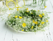 Wreath of cow parsley and buttercups on plate as table decoration for 60th birthday