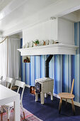 Wood-burning stove against blue-striped wallpaper in dining room