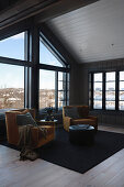 Ochre velvet armchairs next to panoramic window in wooden house