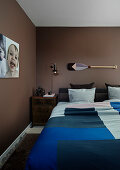 Double bed and bedside cabinet in bedroom with brown walls