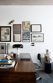 Wooden desk below various prints on wall