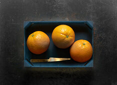 Three oranges in a wooden crate