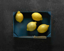 Four lemons in a wooden crate