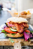Burger with bacon, tomato and cucumber