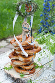 Self-made pretzel tower made of wooden disc and branch, decorated with herb wreaths, ribbons, birch disc with inscription Servus and pretzel