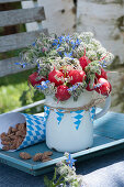 Edible bouquet of radishes, borage and Bibernelle decorated in Bavarian style and a bag with roasted almonds